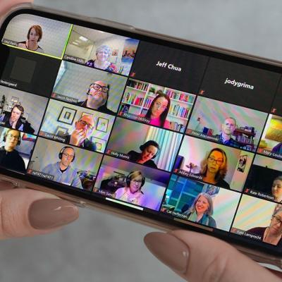 Lady holding iPhone participating in Zoom call