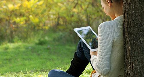 Lady in park using iPad under a tree