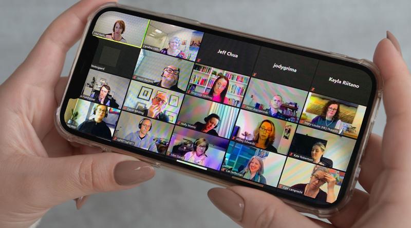 Lady holding iPhone participating in Zoom call