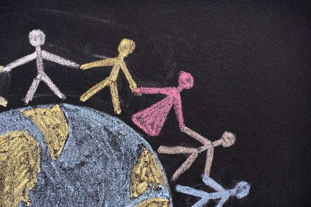 Chalk illustration of stick people holding hands around the world