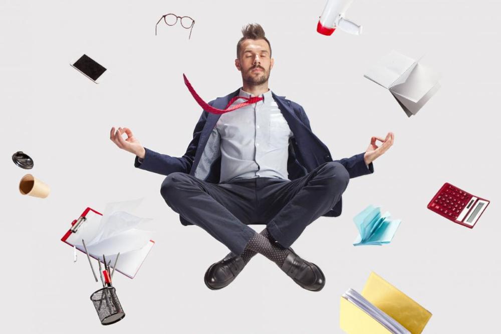 Funny man in suit cross-legged floating like a meditation with objects around him