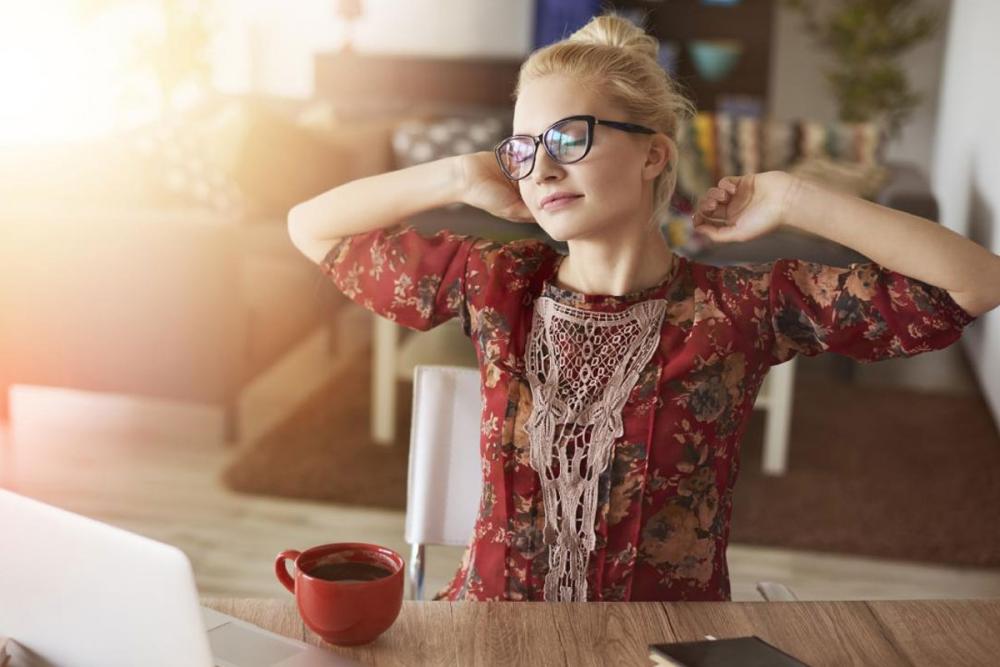 Young lady in red top stretching arms at desk