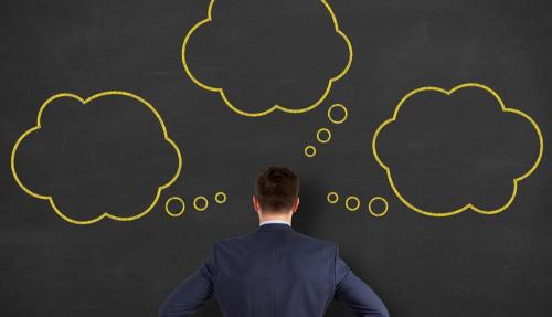man in suit staring at blackboard with sketches on it