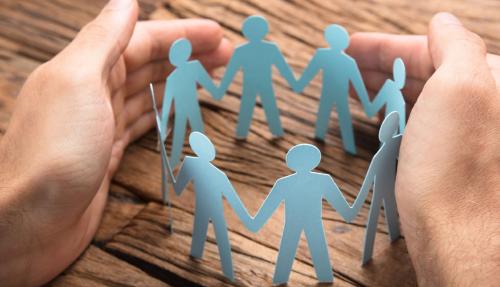 Team concept of hands holding cutout paper people folded in circle