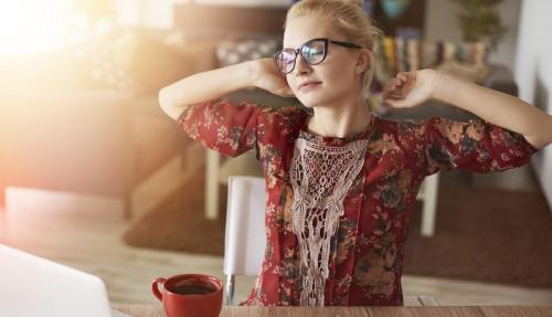 Young lady in red top stretching arms at desk