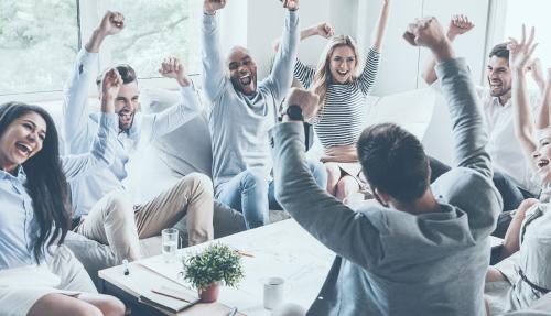 Large team in office at desks all celebrating
