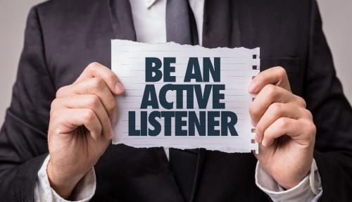 Man in suit holding a sign that says be an active listener