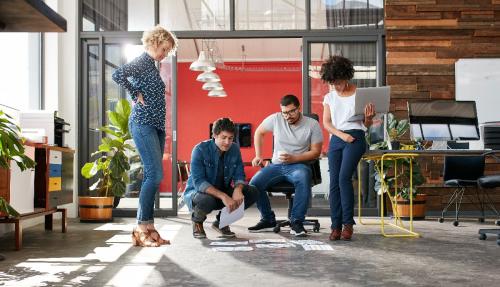 Young trendy team looking over documents on office floor together