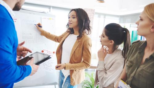Lady presenting to small group of colleagues using whiteboard