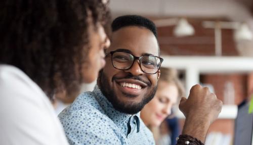 Black man smiling with woman in foreground next to him