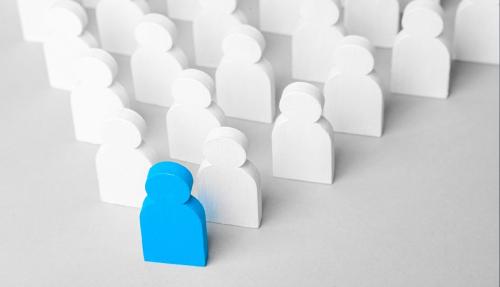 People shaped blocks all white in a row with a blue one standing out