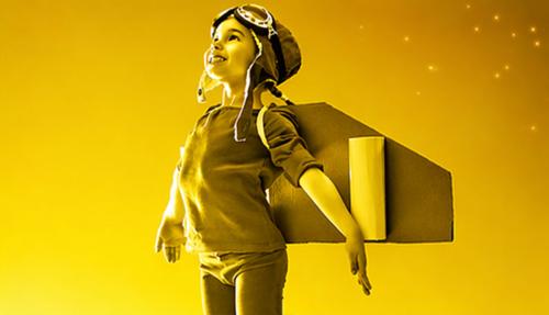 Child with wings pretending takeoff yellow background