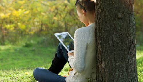 Lady reading iPad in park