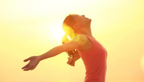 Lady stretching arms on beach at sunset
