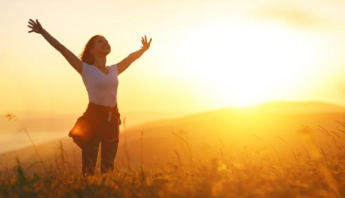 Lady arms in air outside at sunset